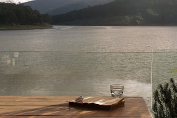 Book with a cup of water and glasses on a dock